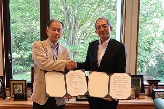 協定書に署名し、固い握手を交わす渡辺理事長と小林代表取締役社長